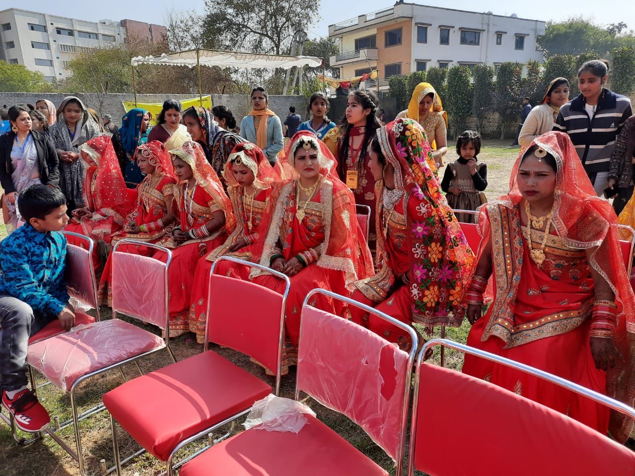 Multiple women dressed as brides sitting on chairs